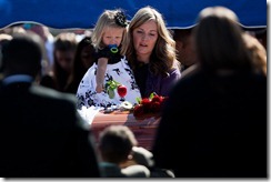 Christy Ivie, wife of Nicholas J. Ivie, holds their daughter as she lays a rose on his casket at his graveside service at the Spanish Fork City Cemetery on Thursday, Oct. 11, 2012. Ivie, a U.S. Border Patrol agent, was shot and killed last week near the Mexican border when agents opened fire on each other, mistakenly believing they were firing on drug smugglers. SPENSER HEAPS/Daily Herald
